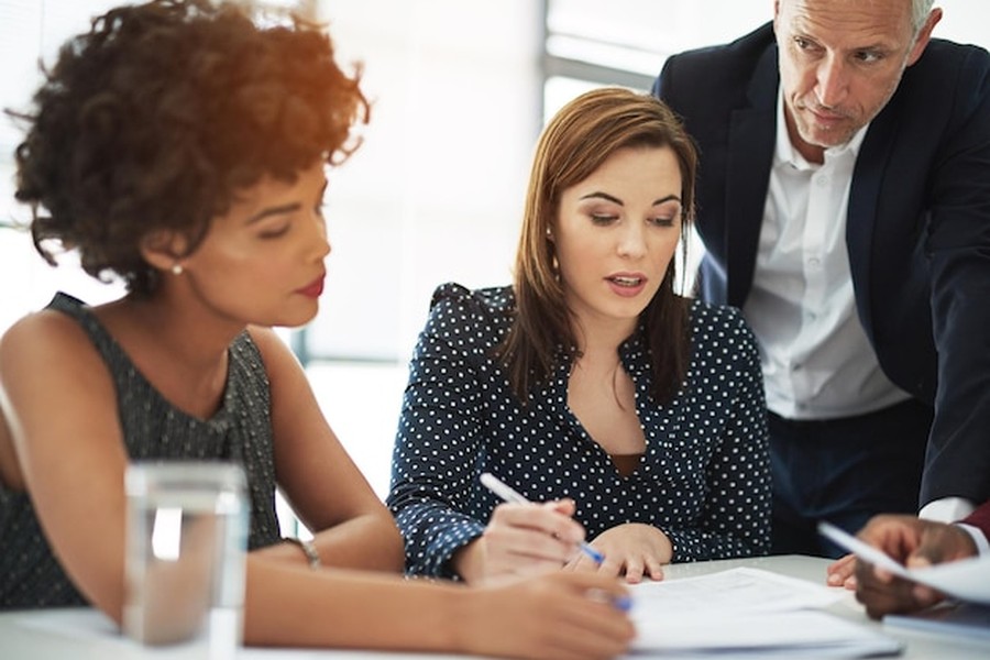 Trois professionnels en réunion discutant de transparence pour savoir comment découvrir le salaire de vos collègues grâce à la loi 2026.