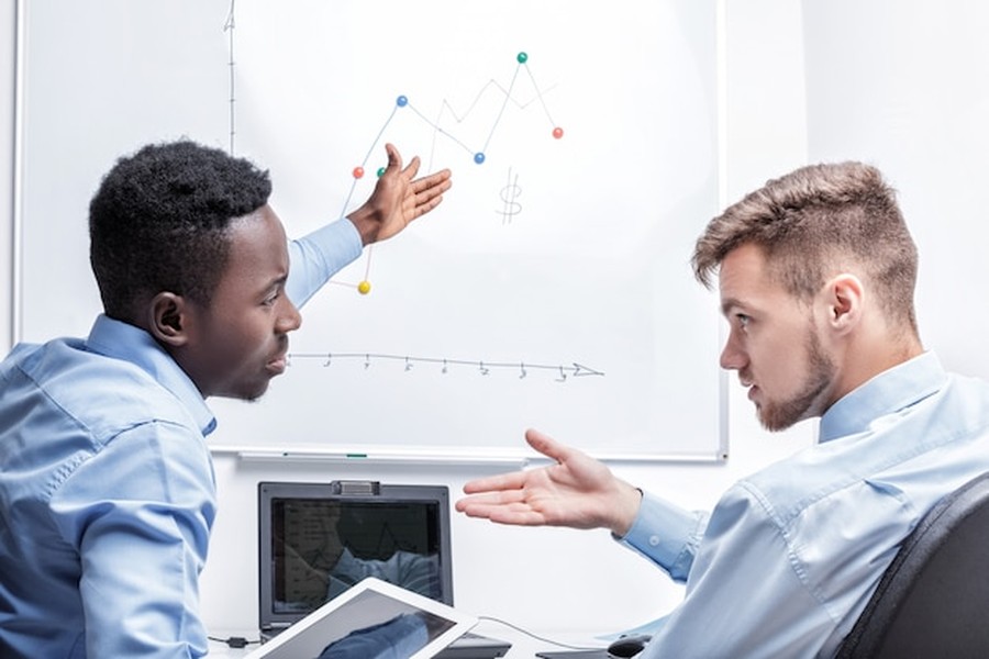 Deux professionnels en pleine discussion devant un graphique, illustrant les enjeux d'un Entretien d'embauche : comment réussir son évaluation face aux logiciels d'analyse émotionnelle.