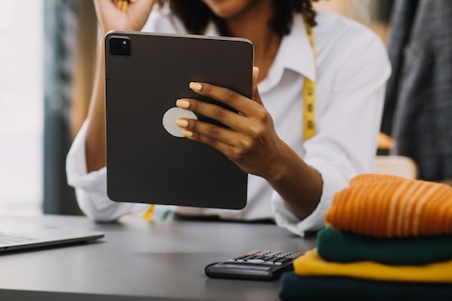 Une experte de la mode utilise une tablette numérique pour réussir l'intégration du Passeport Numérique des Produits (DPP) textile 2026 près de vêtements en maille.