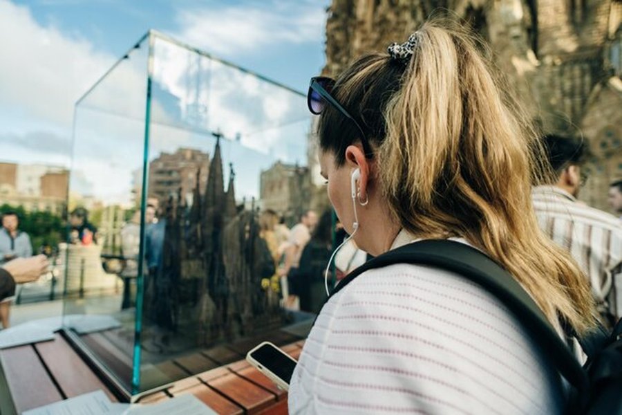 Une voyageuse observe une maquette architecturale sous verre, une étape essentielle avant de choisir des Destinations Miroirs : Les alternatives secrètes pour voyager sans subir les taxes de surtourisme.