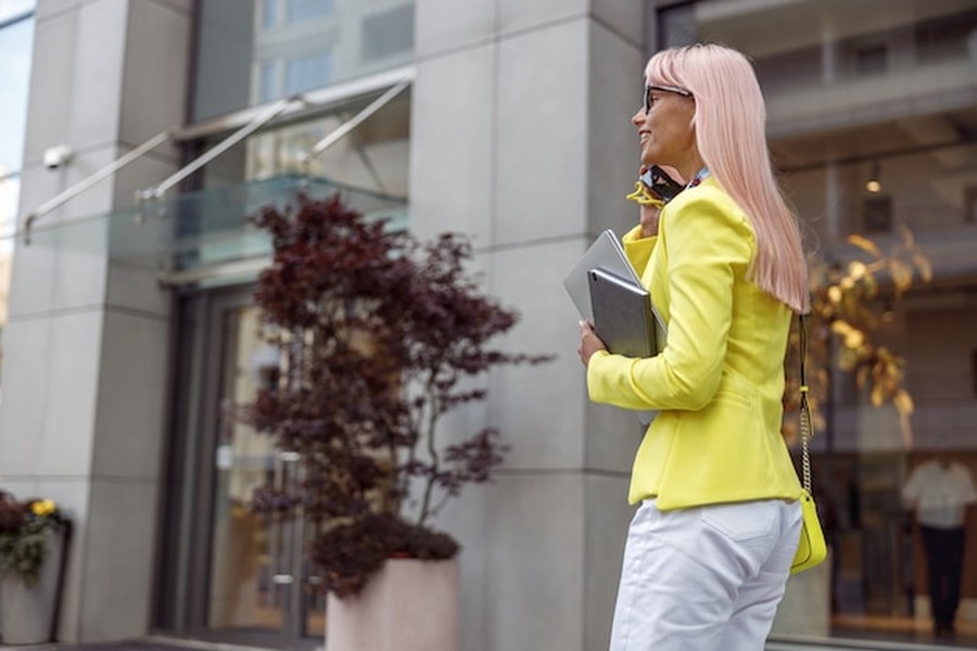 Une femme d'affaires dynamique devant un bâtiment moderne, prête à transformer un local commercial en habitation : les nouvelles simplifications administratives de 2026 facilitent ces démarches.