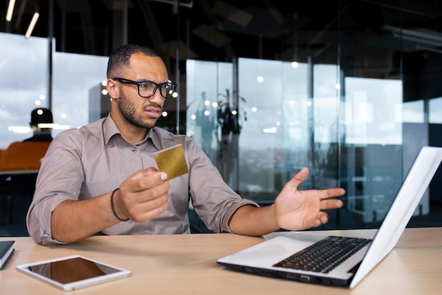 Un homme inquiet examine une transaction suspecte sur son ordinateur pour protéger ses comptes bancaires contre les arnaques au deepfake : les nouvelles garanties d'assurance en 2026.