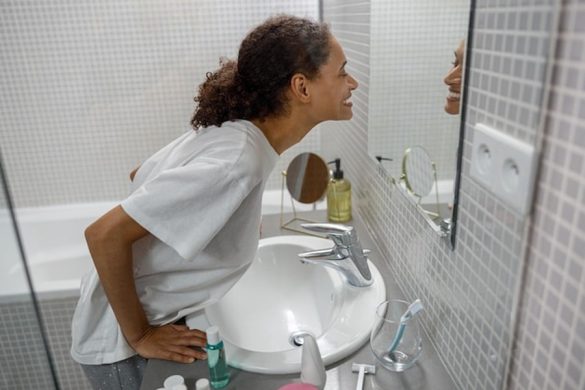 Une femme souriante dans sa salle de bain réfléchissant à comment détourner l'eau de sa douche pour alimenter ses WC à moindre coût.